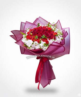 دسته گلی شامل رزهای قرمز و گل‌های سفید آلسترومریا، پیچیده شده در کاغذ بنفش، که توسط شخصی در دست گرفته شده است.